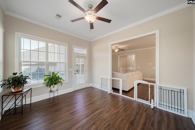 unfurnished room with visible vents, crown molding, baseboards, and wood finished floors