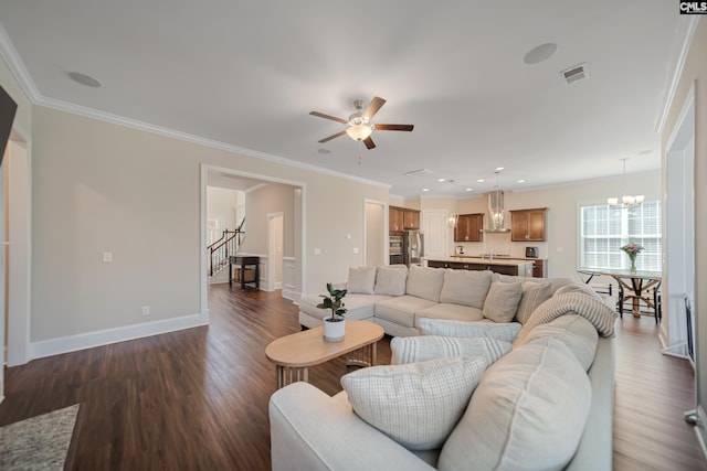 living room featuring baseboards, dark wood-type flooring, crown molding, and ceiling fan with notable chandelier