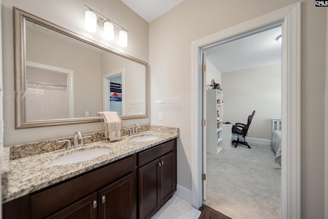 full bathroom with double vanity, baseboards, and a sink