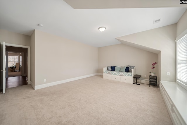 living area with visible vents, baseboards, light colored carpet, and a healthy amount of sunlight