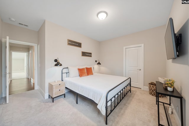 bedroom with attic access, baseboards, visible vents, and light carpet