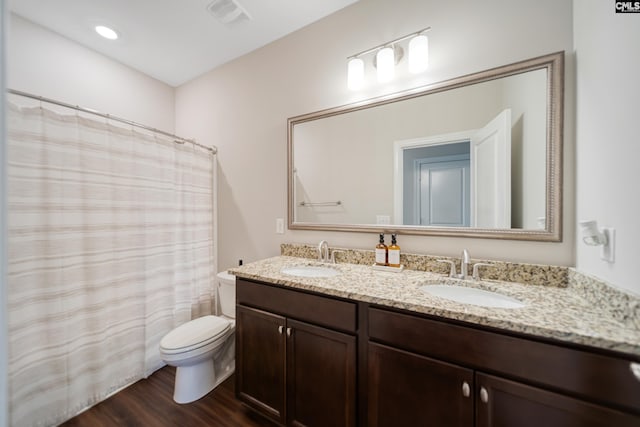 bathroom with toilet, wood finished floors, visible vents, and a sink