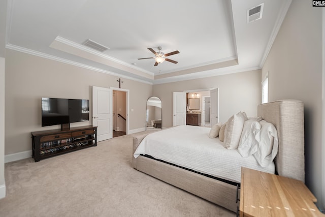 carpeted bedroom with a tray ceiling, visible vents, arched walkways, and baseboards