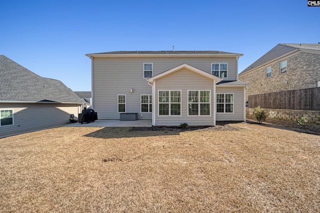 rear view of property featuring a patio, a yard, and fence