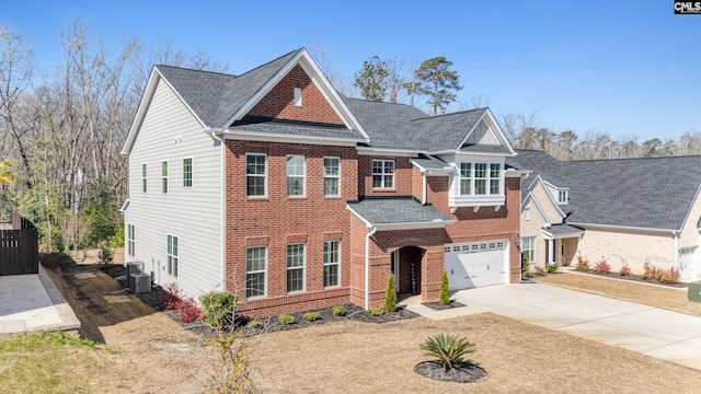 view of front of house with brick siding, a shingled roof, concrete driveway, central AC unit, and a garage