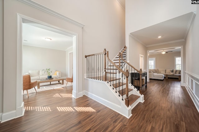 stairs with a ceiling fan, crown molding, baseboards, and wood finished floors