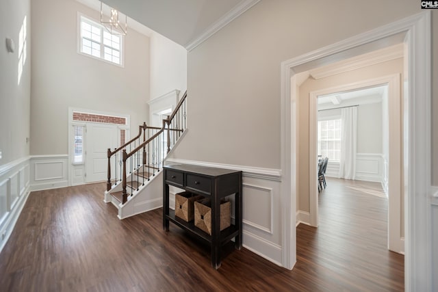 entrance foyer featuring stairway, a chandelier, dark wood finished floors, and a decorative wall