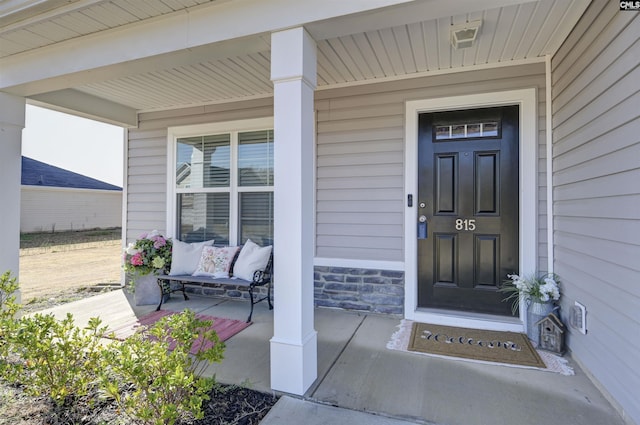 entrance to property with stone siding and a porch