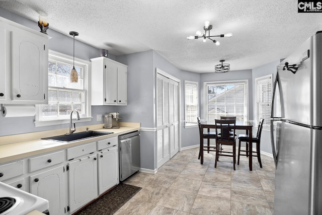 kitchen featuring plenty of natural light, appliances with stainless steel finishes, white cabinetry, and a sink