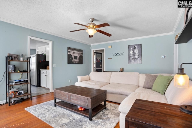 living area featuring a textured ceiling, a ceiling fan, wood finished floors, and ornamental molding