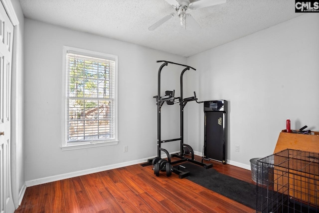 exercise area with baseboards, a textured ceiling, wood finished floors, and a ceiling fan