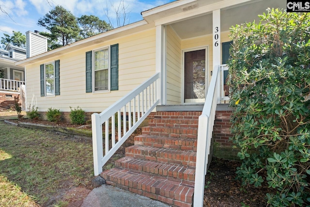 view of exterior entry featuring brick siding and a chimney