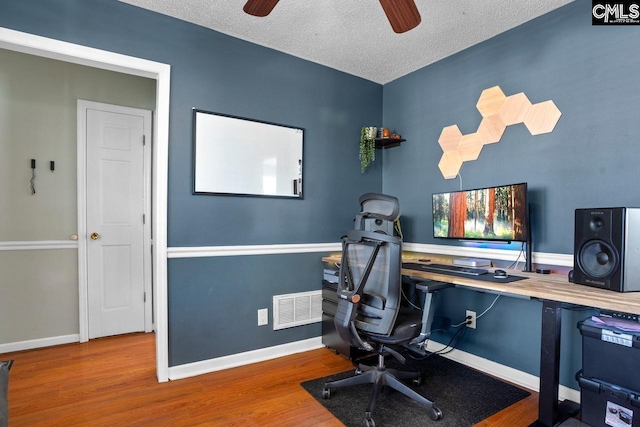 office with wood finished floors, visible vents, baseboards, ceiling fan, and a textured ceiling