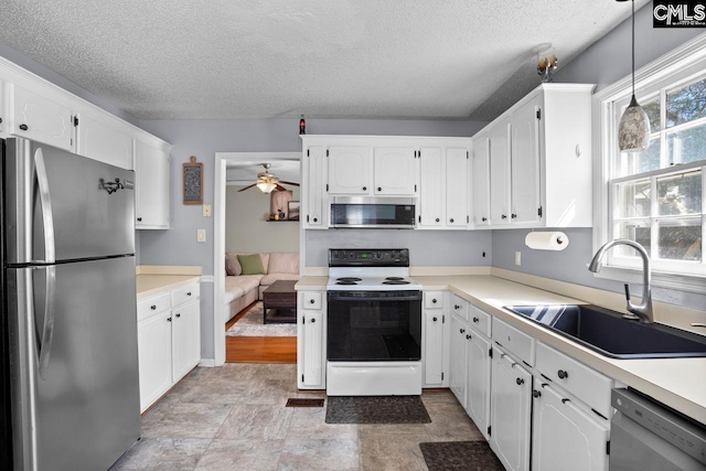 kitchen featuring a sink, light countertops, appliances with stainless steel finishes, a textured ceiling, and white cabinetry