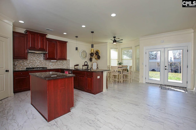 kitchen featuring a peninsula, visible vents, reddish brown cabinets, and a kitchen island