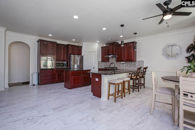 kitchen with marble finish floor, a sink, stainless steel appliances, arched walkways, and reddish brown cabinets