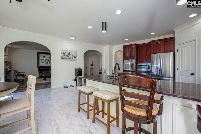 kitchen featuring arched walkways, marble finish floor, reddish brown cabinets, and stainless steel appliances