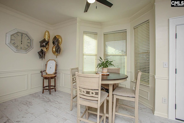 dining space with a decorative wall, wainscoting, marble finish floor, and ornamental molding