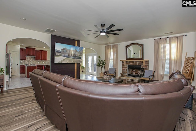 living room with visible vents, arched walkways, a healthy amount of sunlight, and a fireplace