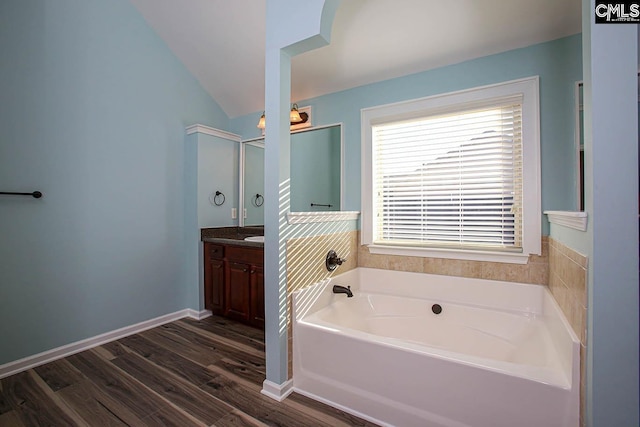 full bathroom with baseboards, a garden tub, vaulted ceiling, wood finished floors, and vanity