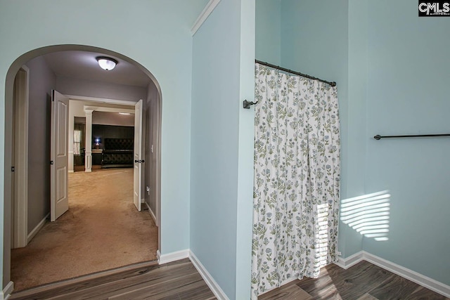 hall with wood finished floors, baseboards, and arched walkways