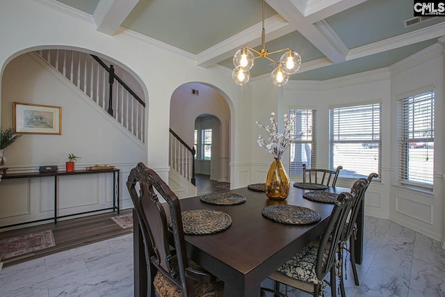 dining space featuring beam ceiling, marble finish floor, a chandelier, and a decorative wall