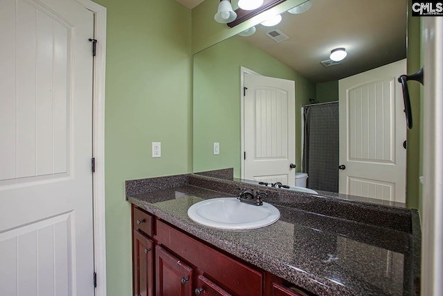 bathroom featuring visible vents, toilet, vanity, and vaulted ceiling