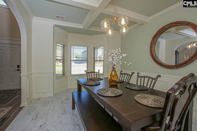 dining space with a wainscoted wall, a decorative wall, visible vents, and coffered ceiling