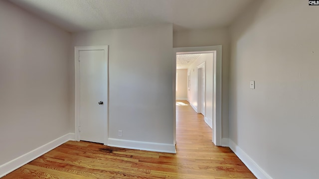 unfurnished bedroom with baseboards, light wood-style floors, and a textured ceiling