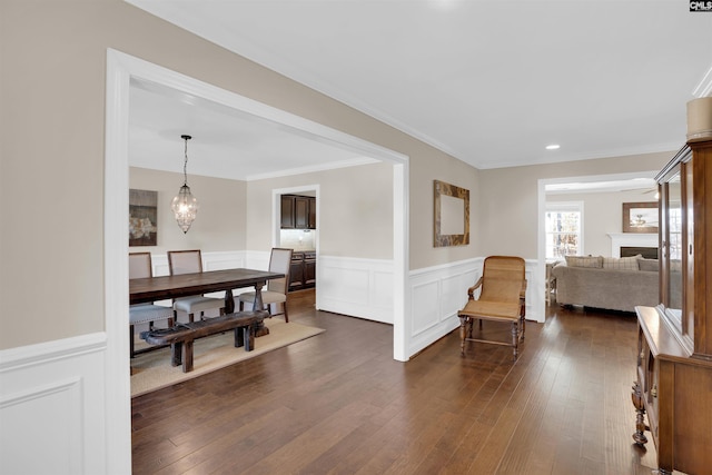 interior space featuring dark wood-style floors, a wainscoted wall, crown molding, and a notable chandelier