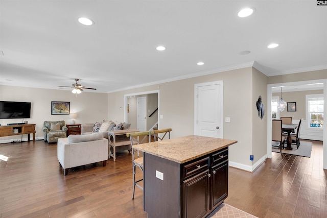 kitchen with recessed lighting, a kitchen bar, baseboards, and dark wood-type flooring