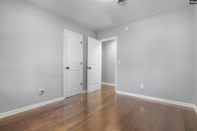 empty room featuring visible vents, baseboards, and wood finished floors