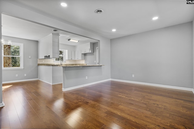 kitchen featuring visible vents, decorative backsplash, a peninsula, dark wood-style floors, and white cabinetry