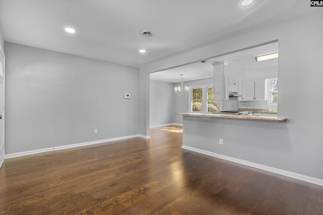 unfurnished living room featuring visible vents, recessed lighting, an inviting chandelier, baseboards, and dark wood-style flooring