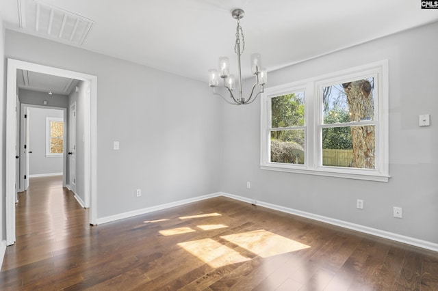 unfurnished room with visible vents, a notable chandelier, attic access, and dark wood-style flooring