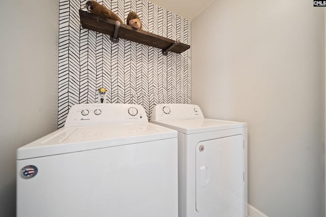 washroom with laundry area, washer and dryer, and an accent wall