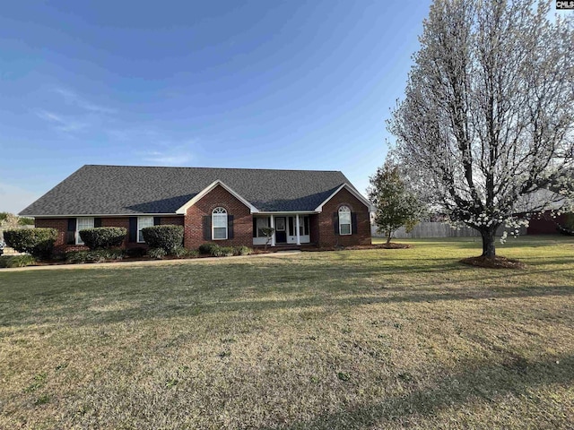 ranch-style home featuring a front yard, fence, and brick siding