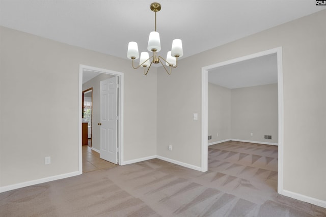 spare room with visible vents, a notable chandelier, carpet, and baseboards