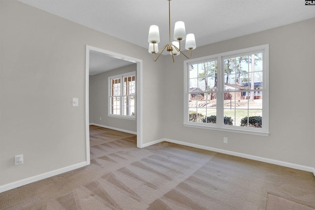 carpeted spare room featuring baseboards and a chandelier