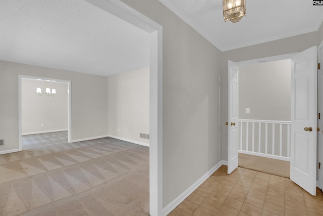 carpeted entrance foyer with a chandelier, visible vents, crown molding, and baseboards