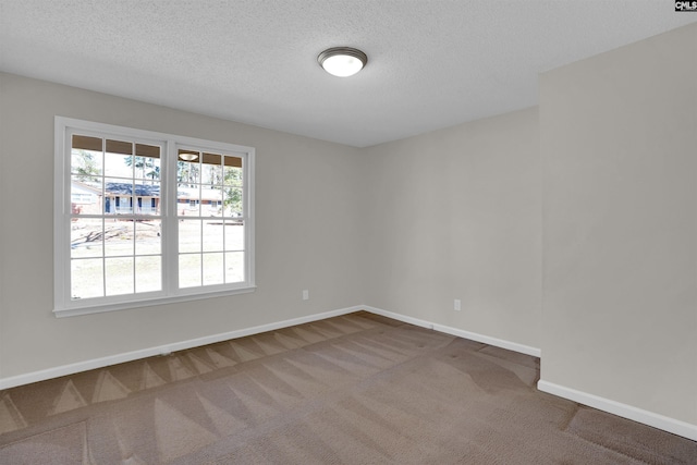 carpeted empty room featuring baseboards and a textured ceiling