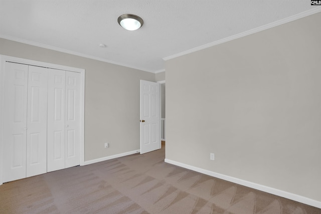 unfurnished bedroom featuring baseboards, carpet floors, a closet, and ornamental molding