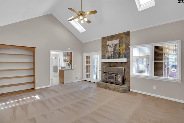 unfurnished living room featuring a skylight, a ceiling fan, carpet floors, and high vaulted ceiling