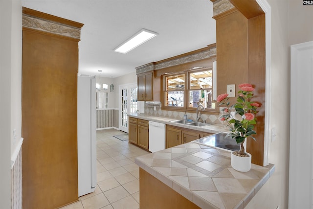 kitchen featuring a sink, decorative light fixtures, tasteful backsplash, white appliances, and light tile patterned floors