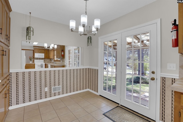 doorway to outside featuring a wealth of natural light, visible vents, a notable chandelier, and light tile patterned flooring