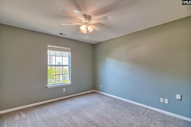 carpeted empty room with a textured ceiling, baseboards, visible vents, and ceiling fan