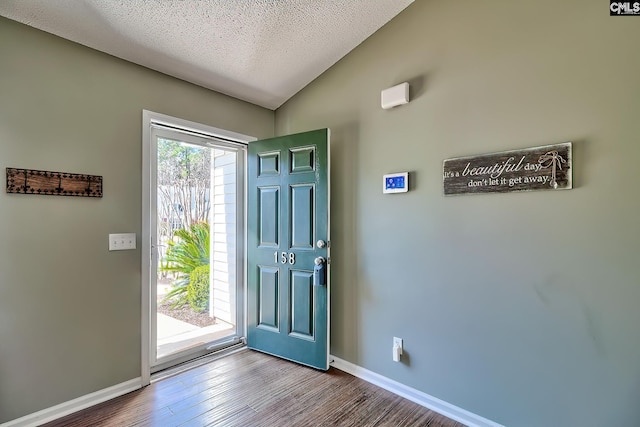 foyer entrance featuring vaulted ceiling, wood finished floors, baseboards, and a textured ceiling