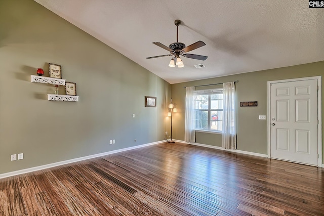 interior space with visible vents, baseboards, lofted ceiling, ceiling fan, and dark wood-style flooring