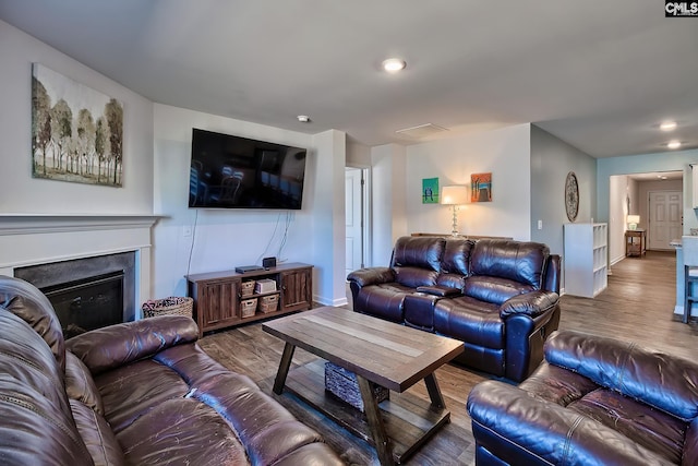 living area with a fireplace, baseboards, and wood finished floors