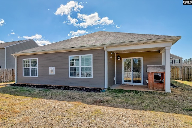 rear view of house with roof with shingles and fence